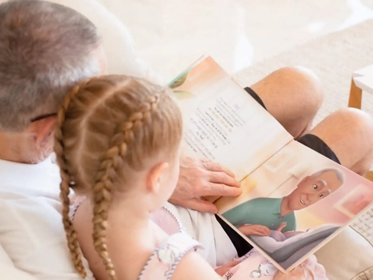 Un nonno e la sua nipote che leggono un libro personalizzato.