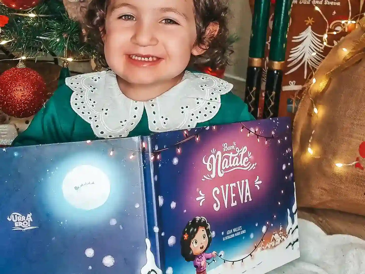 Una bambina mostra il suo regalo di Natale, un libro personalizzato di Urrà Eroi. 